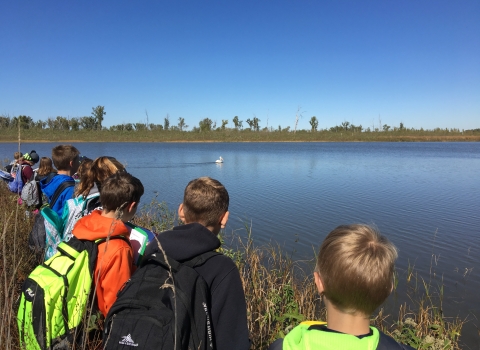 A class of students look out at a body of water.