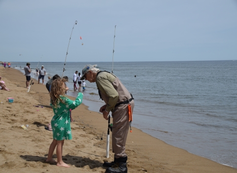 Image of volunteer surf caster with young child on the beach