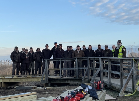 a group of people stand on a boardwalk during a construction project