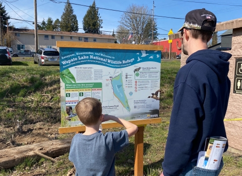 An adult and child read a sign at Wapato Lake National Wildlife Refuge.