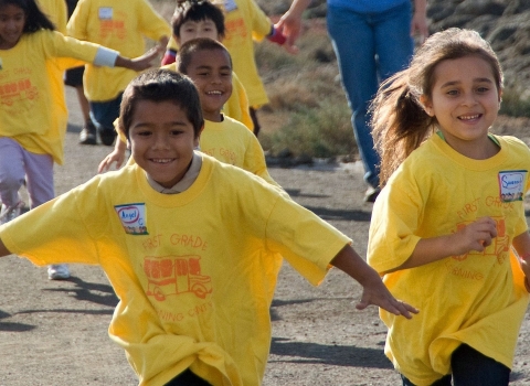 Kids in yellow shirts run at Don Edwards San Francisco Bay National Wildlife Refuge, while on an elementary school field trip.