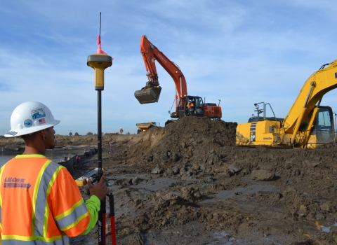 Contractor stands on the left viewing bulldozers level restoration site