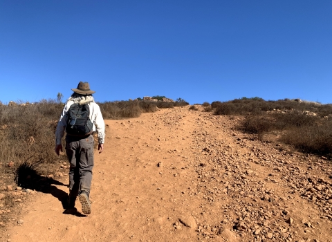 Man on the left of photo hikes up a steep, rocky trail.