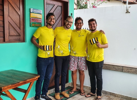 Four people in yellow t-shirts are holding power line markers
