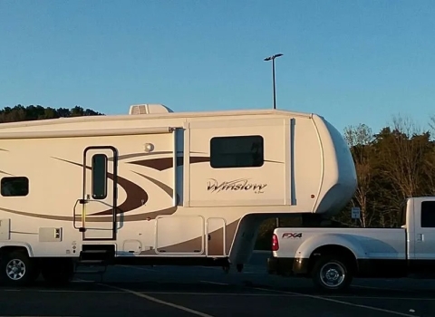 a white pickup truck pulls a long fifth wheel camper