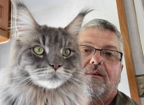Man and gray cat take picture together.