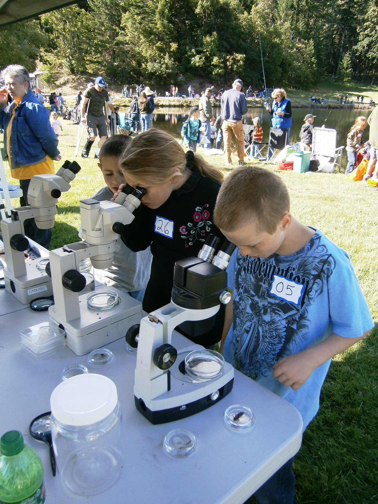 2012 Youth Fishing Derby participants observing aquatic insects through microscopes at FWS booth