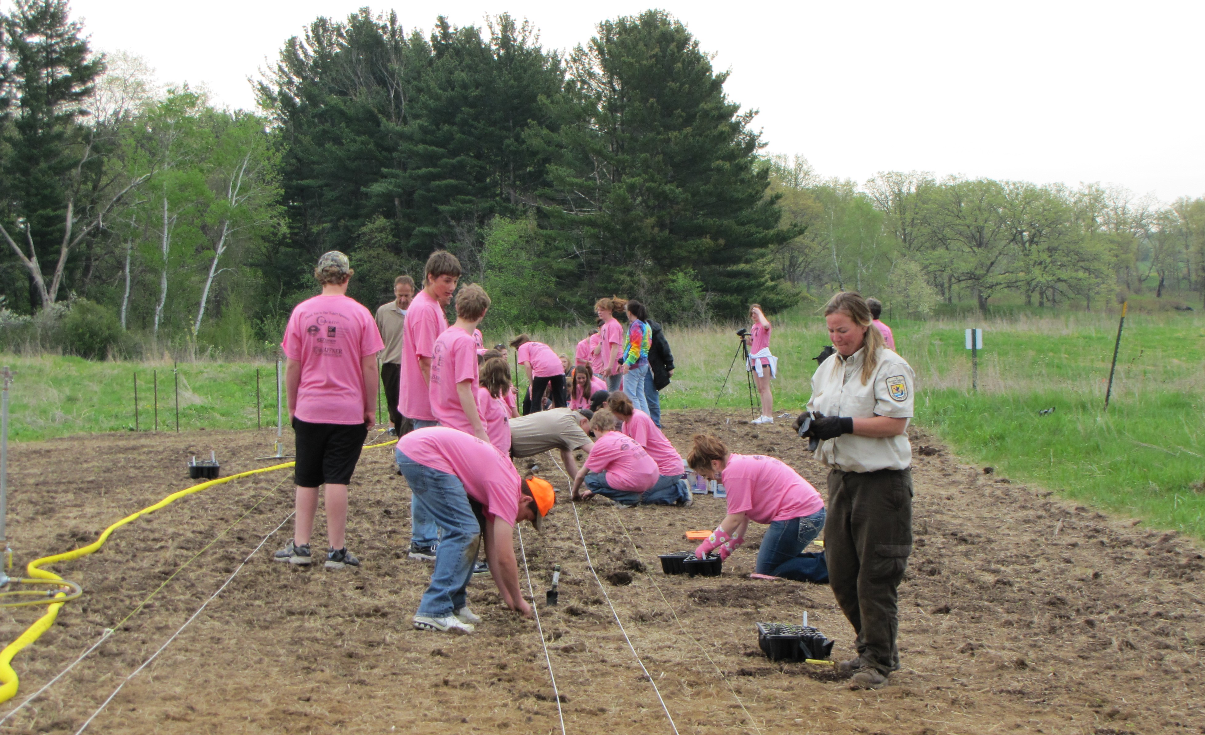 A group of people and a person in a brown uniform are working in a field