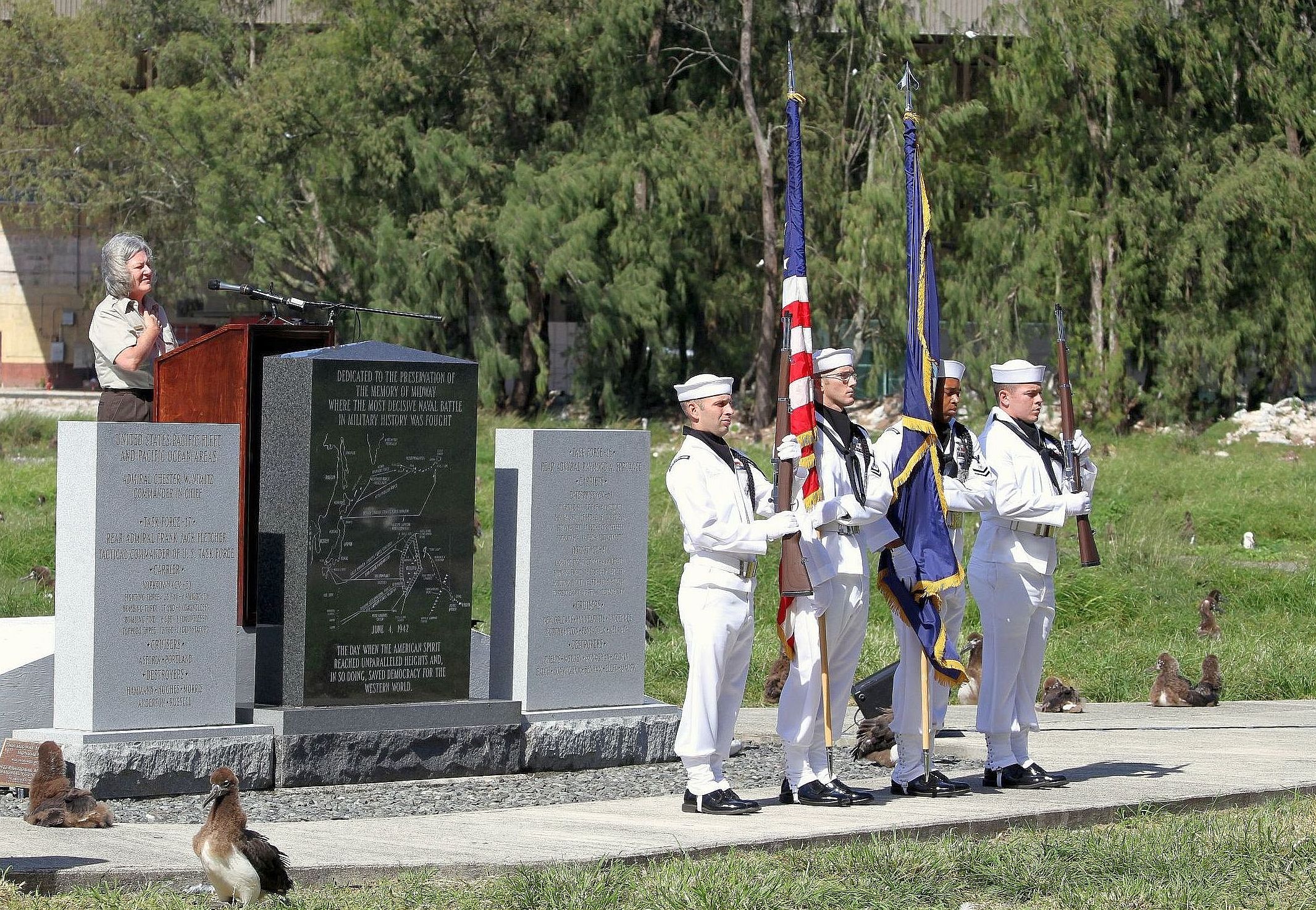 A military color guard standing at attention in front of a granite monument
