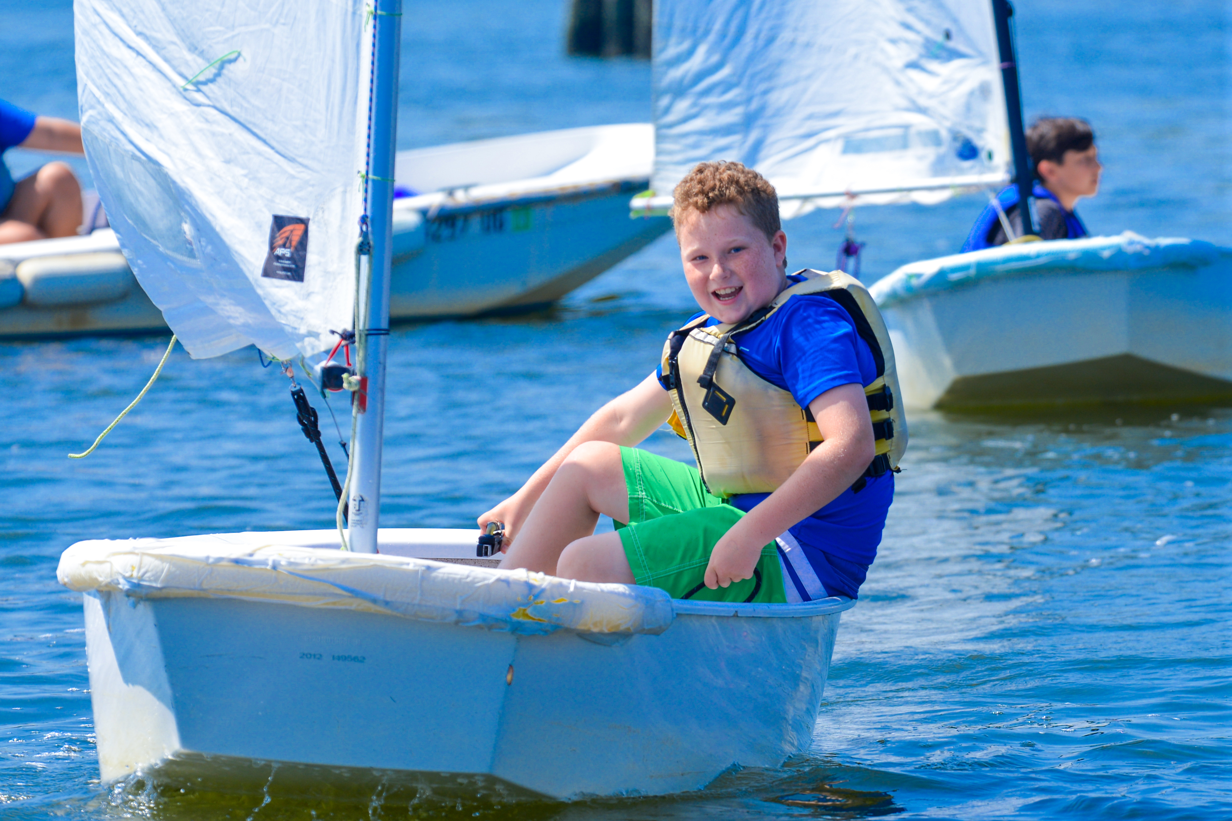 Smiling boy brings his sailboat to shore