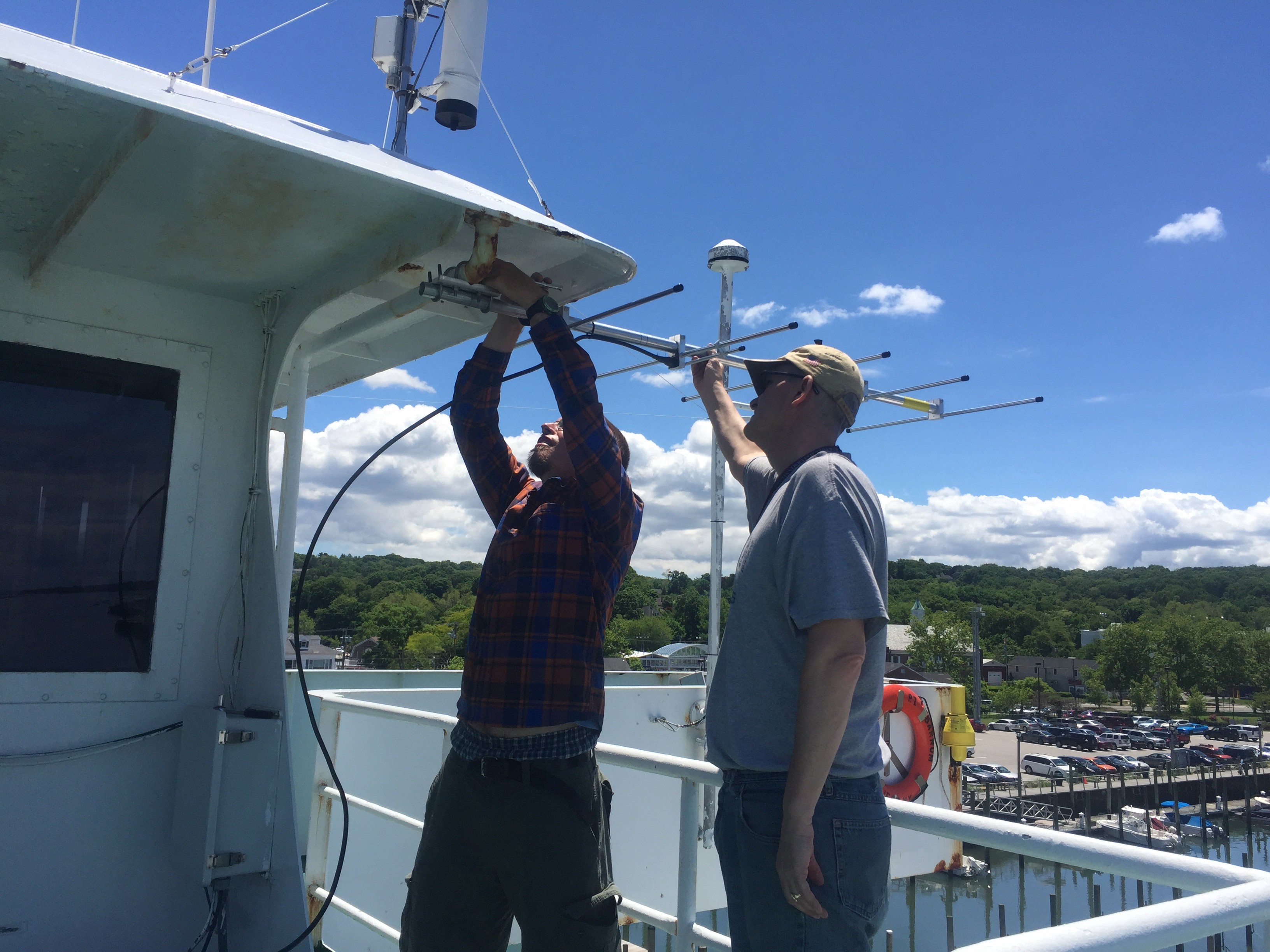 Image of two men installing a tracking antenna on a boat