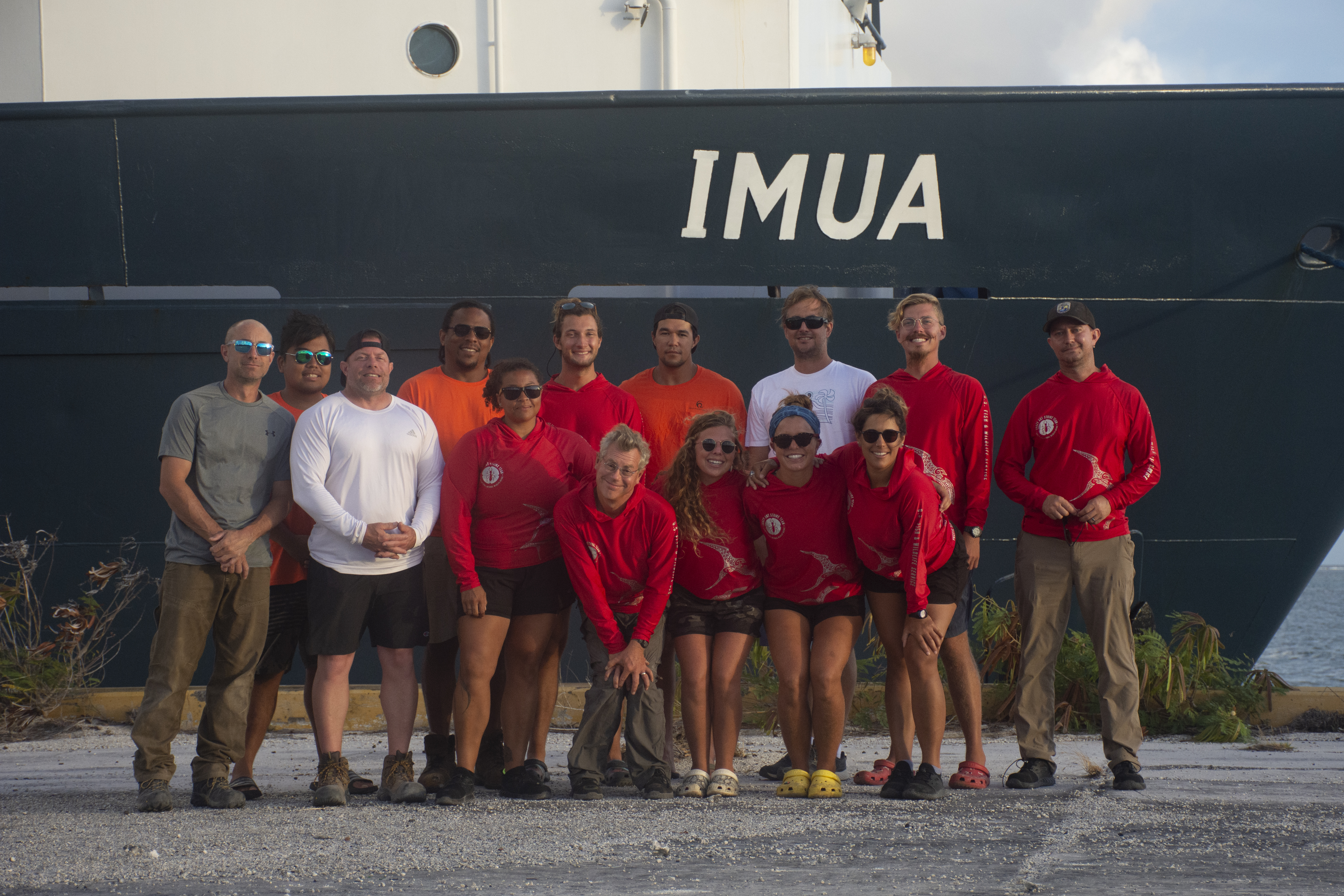 A group of Fish and Wildlife biologists and volunteers, USGS contractors, and boatcrew members of the Imua, stand in front of the boat on Johnston.