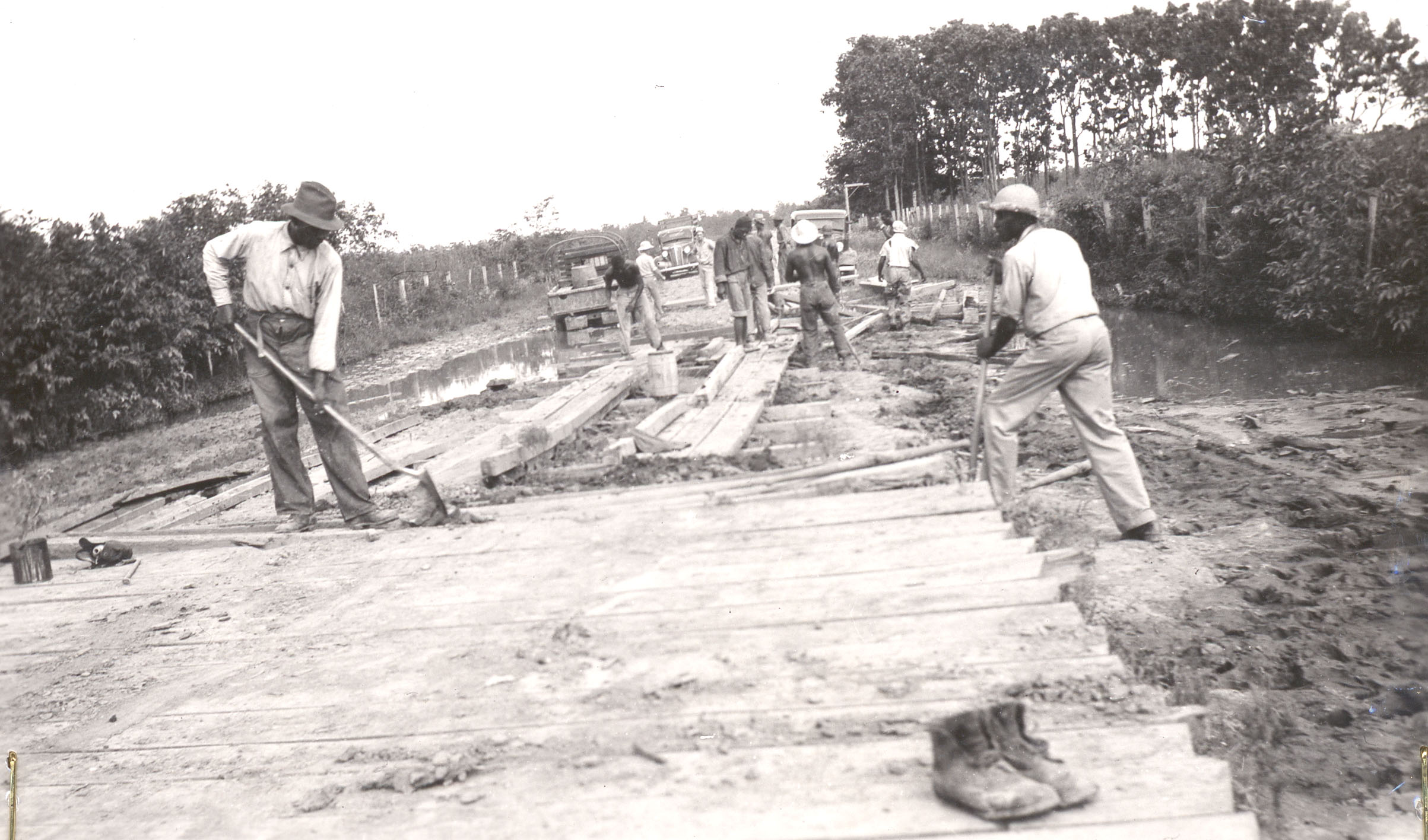 Black and white photo of black men laying wood for a road.