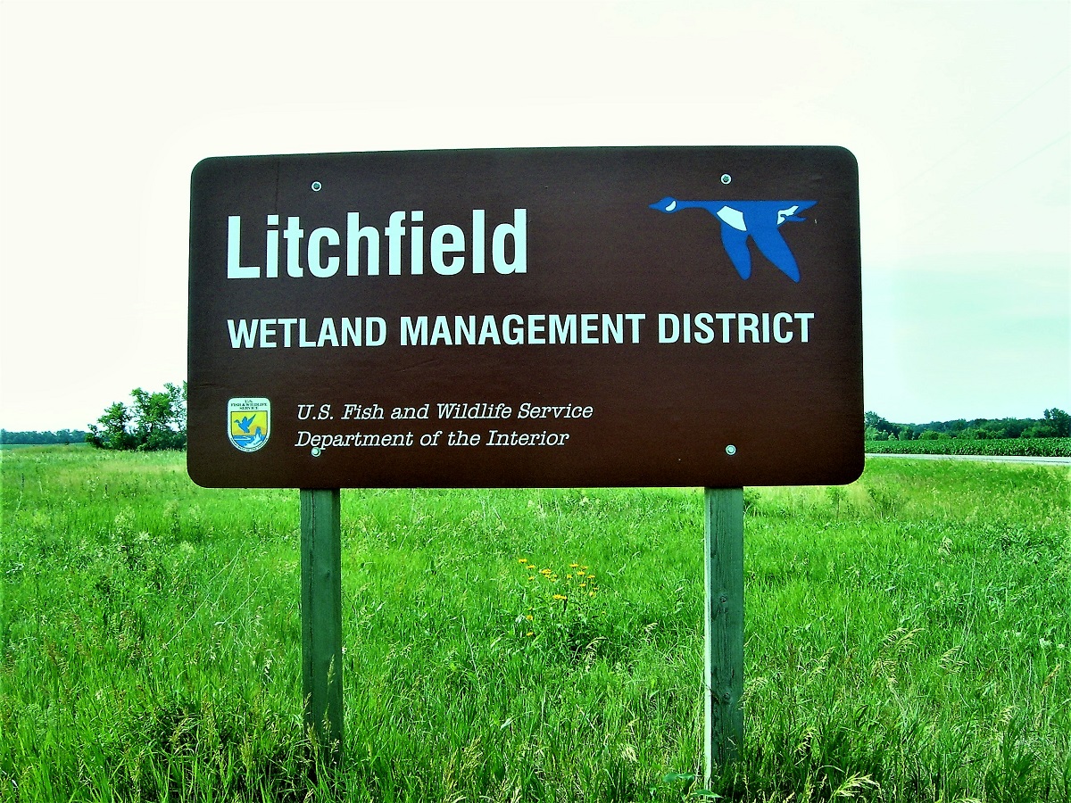 Litchfield Wetland Management District sign on a grassland landscape. 