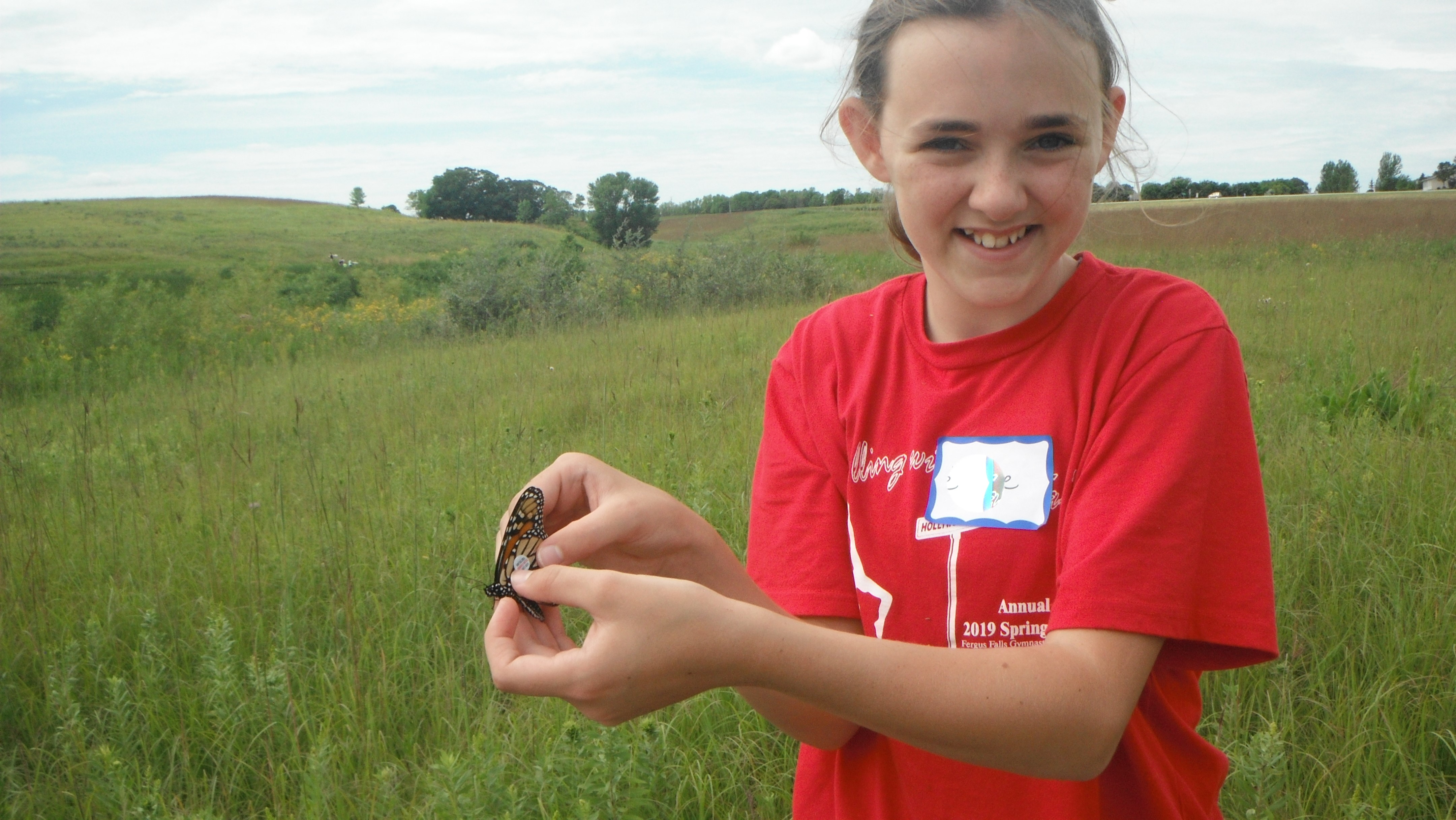 A youth volunteer holds a monarch butterfly she tagged.