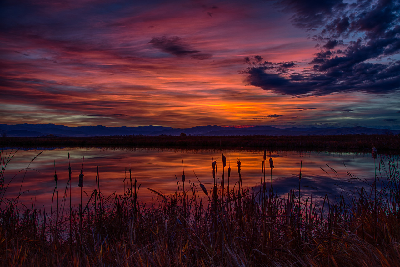 A vibrant red-purple sunset over a lake