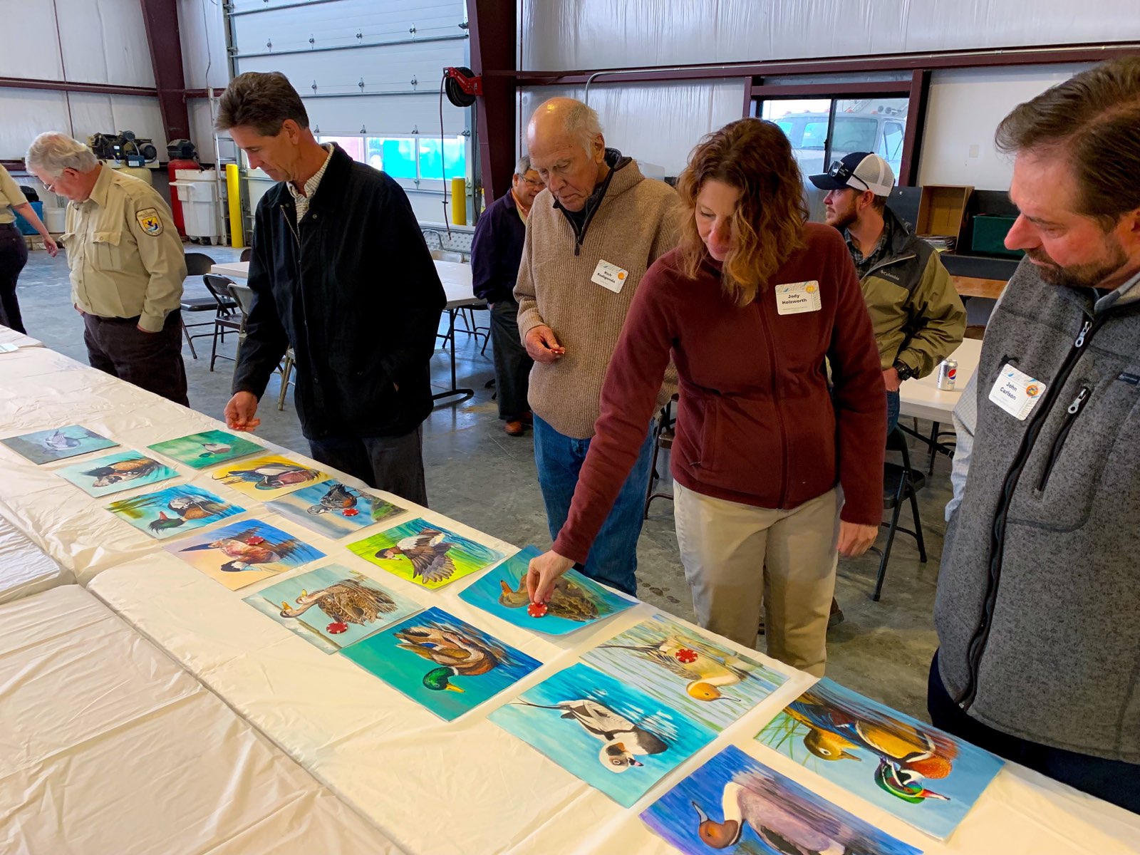 Several judges view waterfowl artwork on a table as a part of the CA JDS Contest in 2019