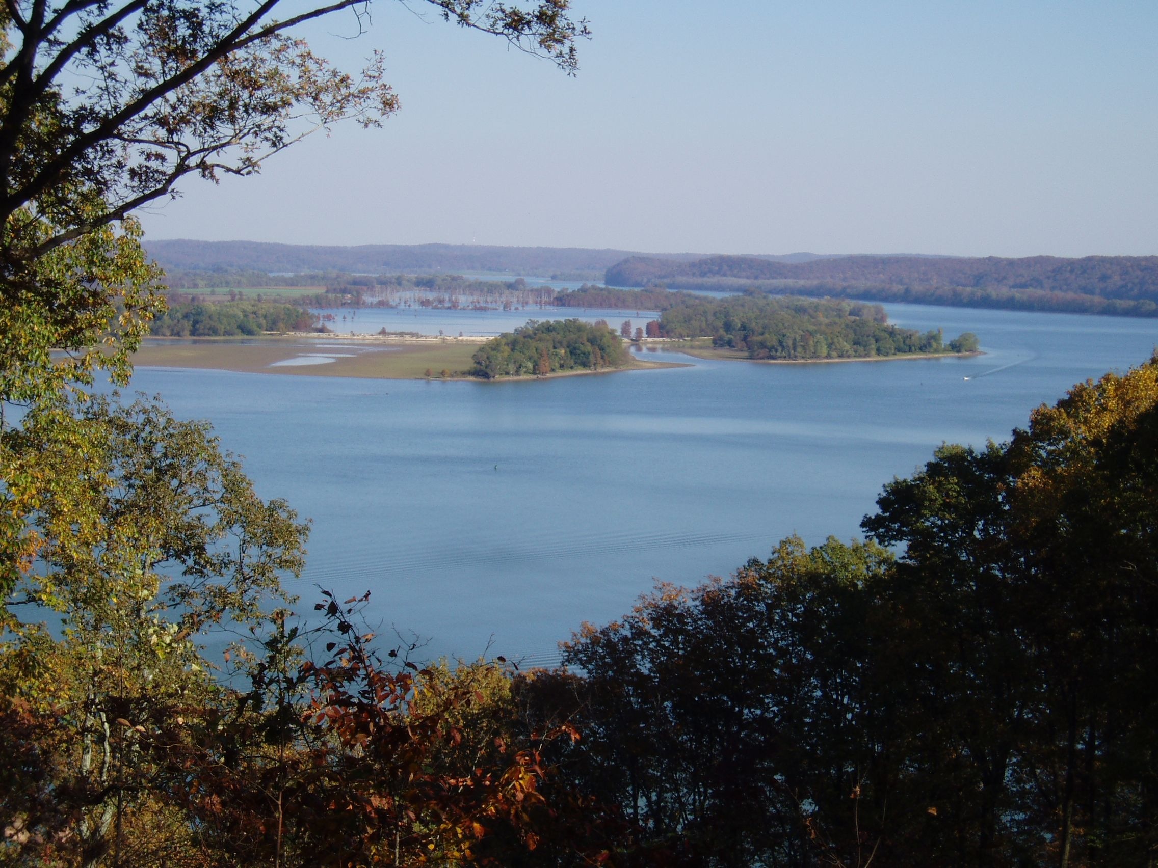 A view of a wide blue river from a forested overlook high above 