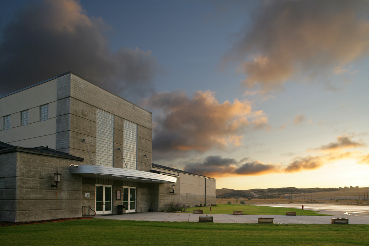Exterior of Fort Peck Interpretive Center building with clouds and hills in the background