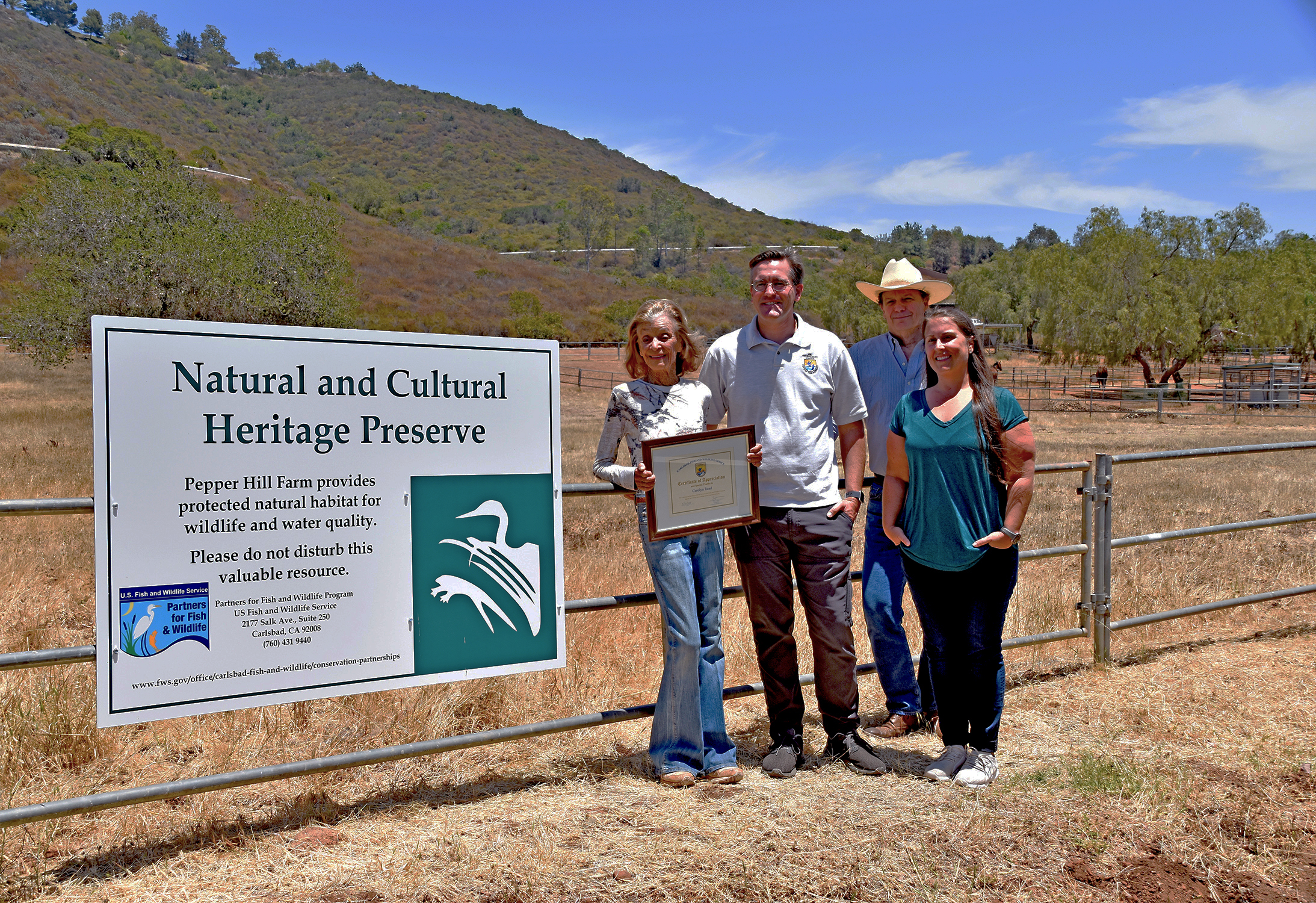two men and two women stand next to a sign that reads Natural and Cultural Heritage Preserve