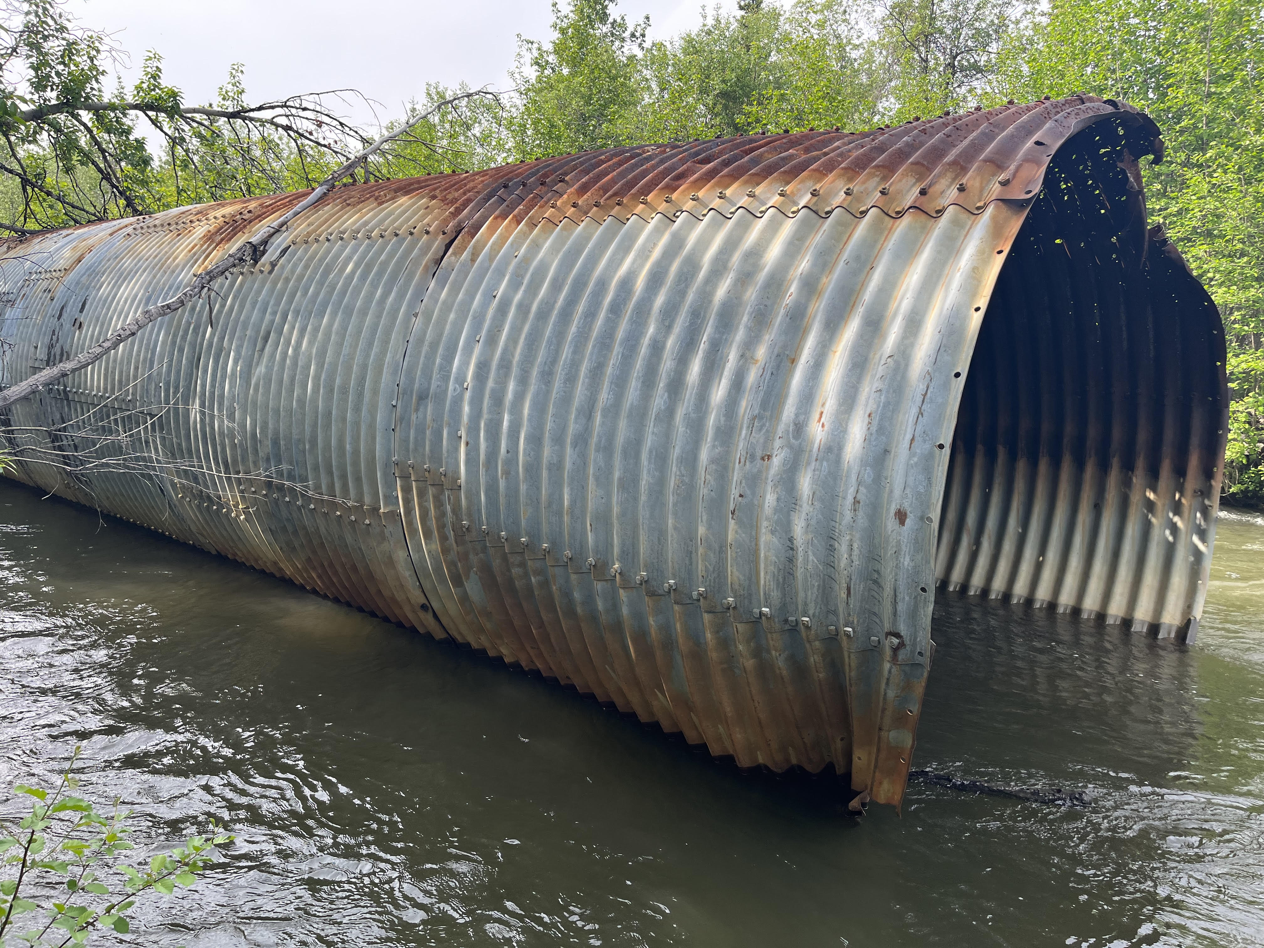 a rusted culvert sits in a river