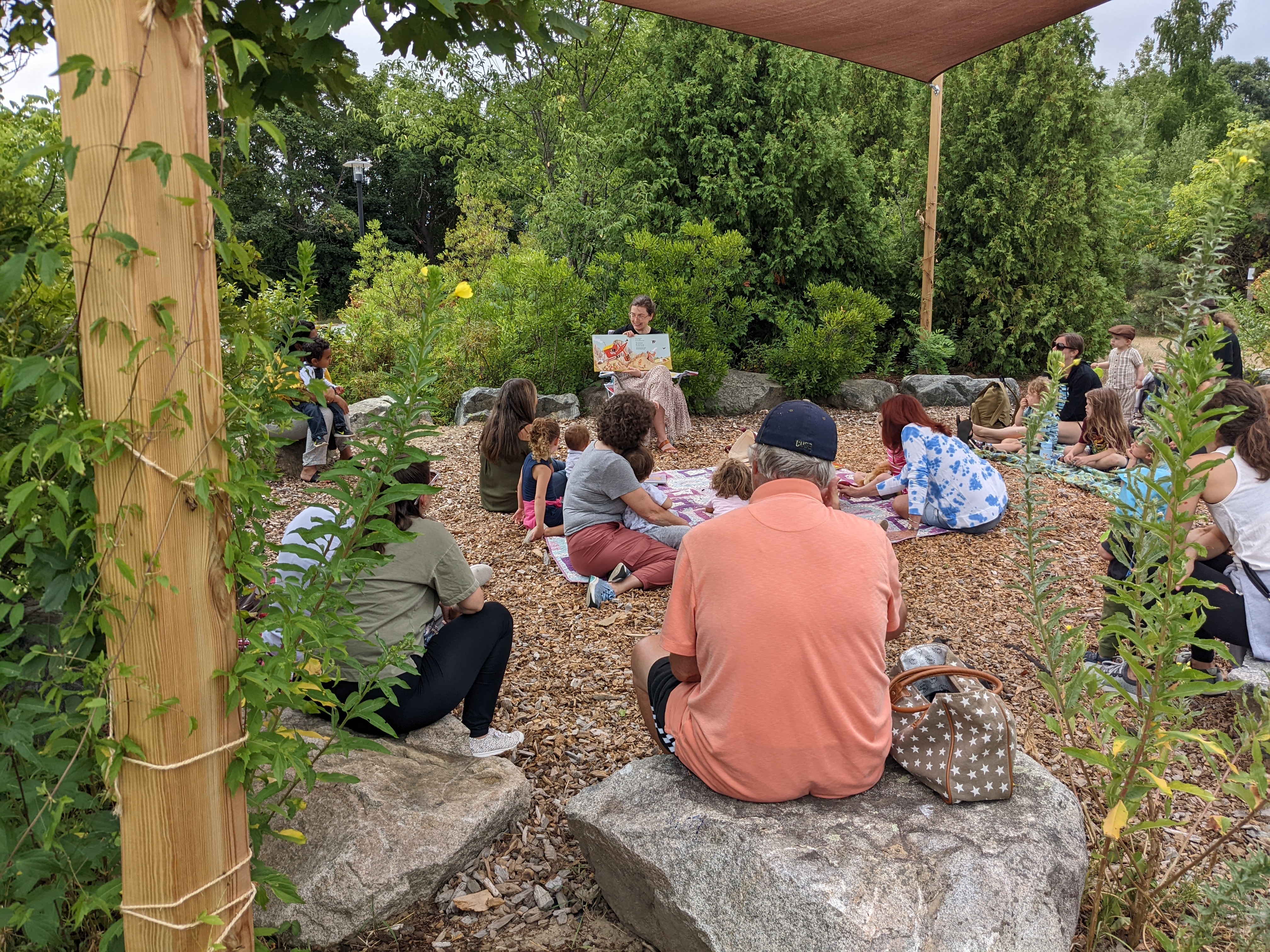 Image of families sitting in a garden listening to a story being read