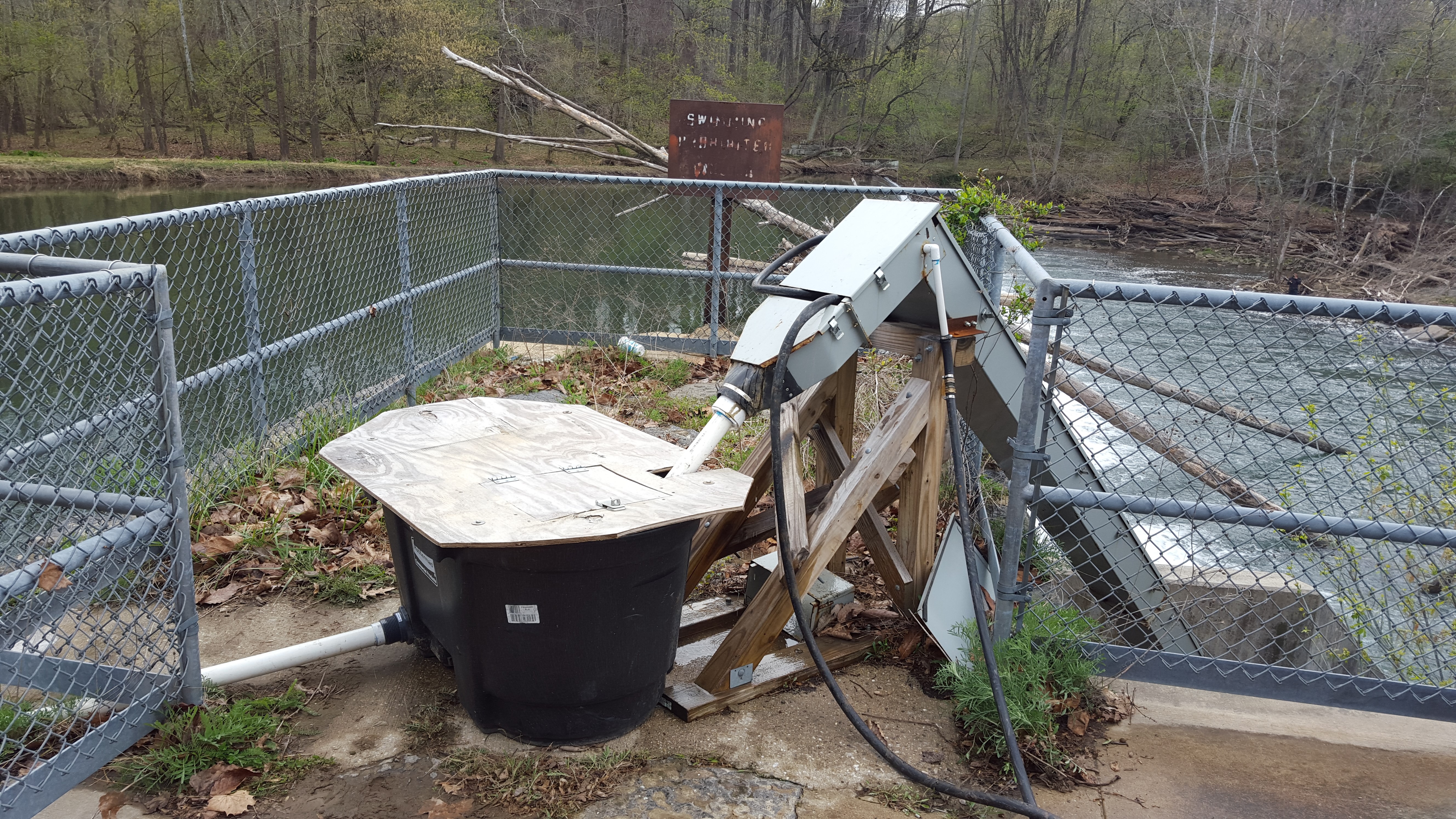 A metal structure between a river and a collection bin at the top of a dam 