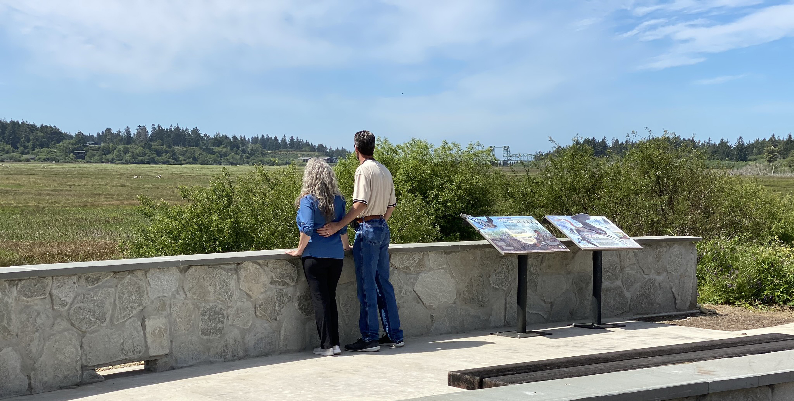 Visitors read interpretive signs at a platform overlooking a marsh