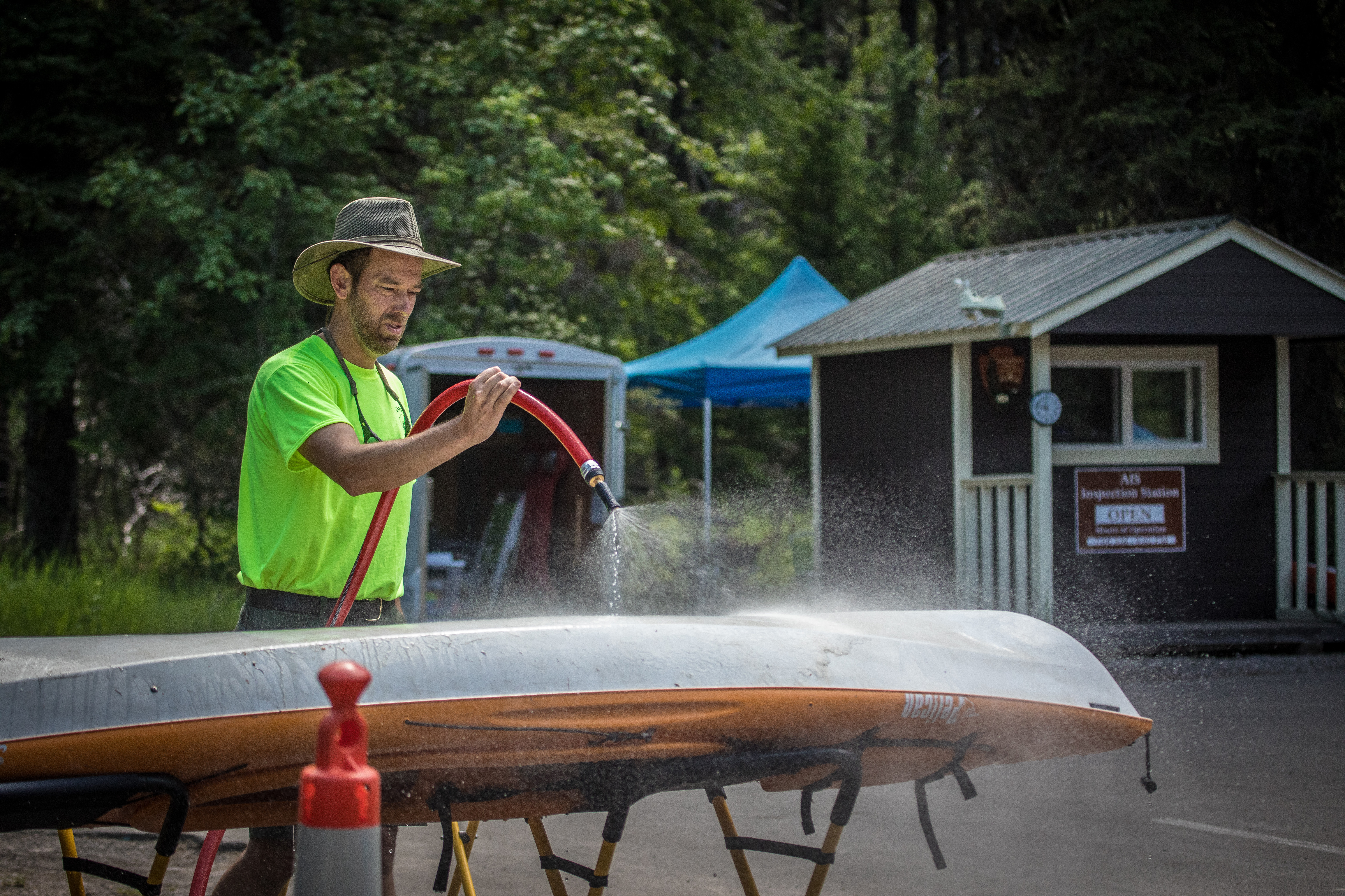A man using a hose to wash a kayak