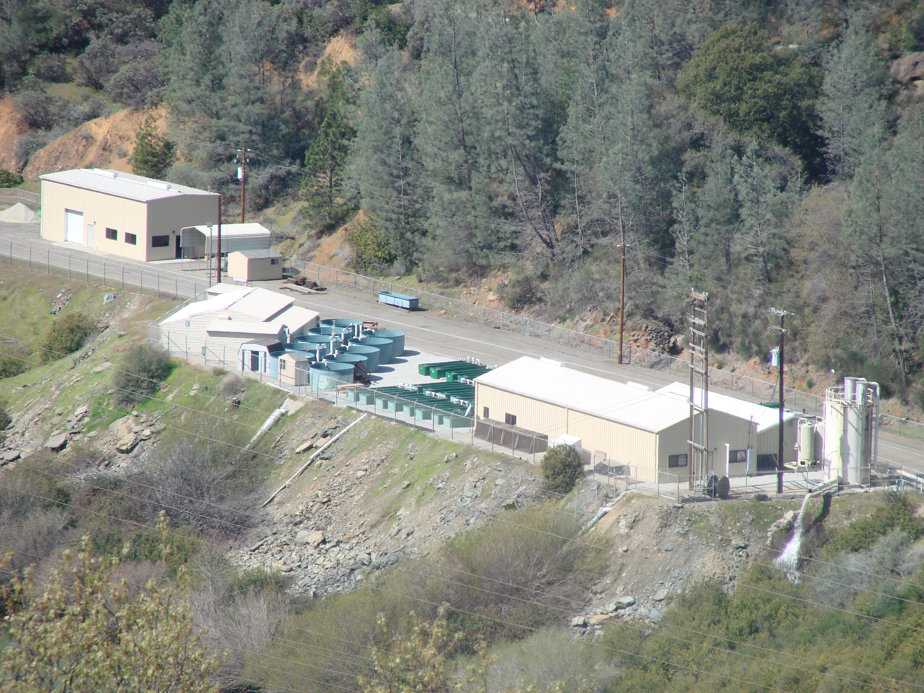 Overhead shot of Livingston Stone National Fish Hatchery.  Photo includes tan buildings and large green circular and rectangular tanks.  