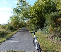 A bicycle parked on the side of a paved trail