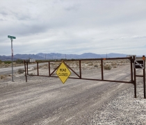 Dirt road with a closed gate, sign reads Road Closed. 