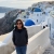Susan Machida stands along cobblestone steps. The buildings of Santorini, Greece, outline the background. 