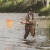 US Fish and WIldlife Biologist, Lindsey Adams, shown wading through water carrying a flag and anchor.