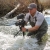 a man in a river holding a camera