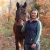 Bri Benvenuti, refuge biological technician at Rachel Carson National Wildlife Refuge, poses with her horse Marshall in fall with colorful leaves framing the two. 