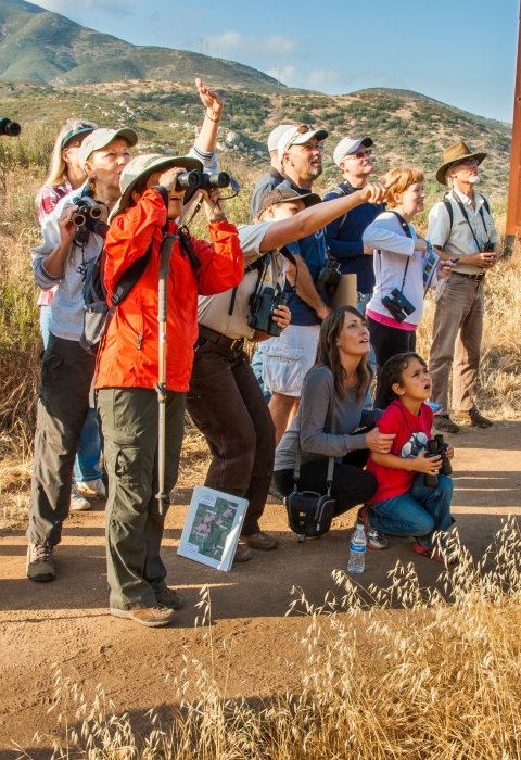Visitors on a ranger-led hike point and react to a wildlife sighting at San Diego National Wildlife Refuge.