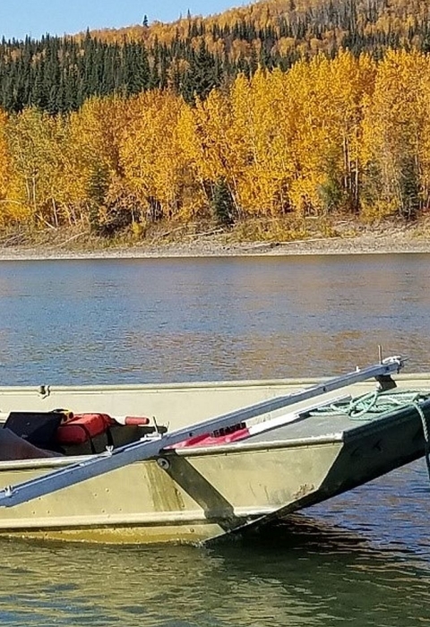 Two men in a small motorboat assessing water quality on a river in fall