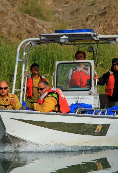men sitting in boat with life vest on in river
