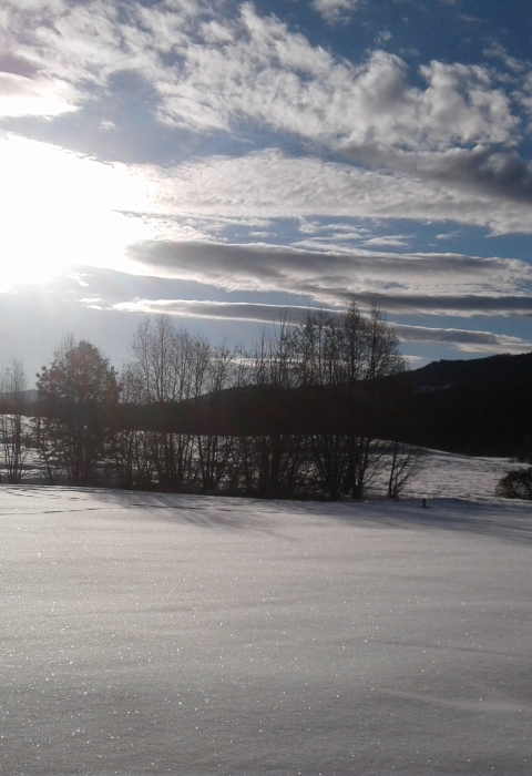 Snow covered hills at Little Pend Oreille National Wildlife Refuge, with sun streaming through scattered clouds. 