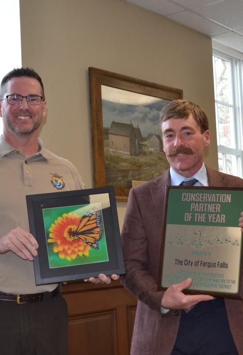 Two adults holding a plaque and a framed print