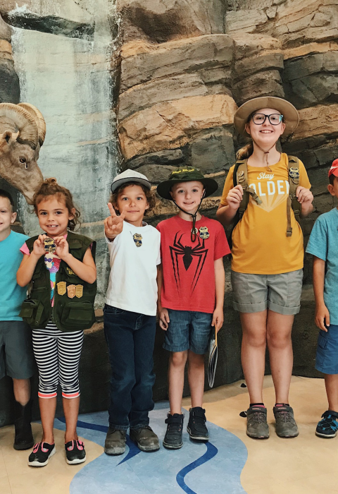 Group of junior rangers standing in front of a visitor center display exhibit