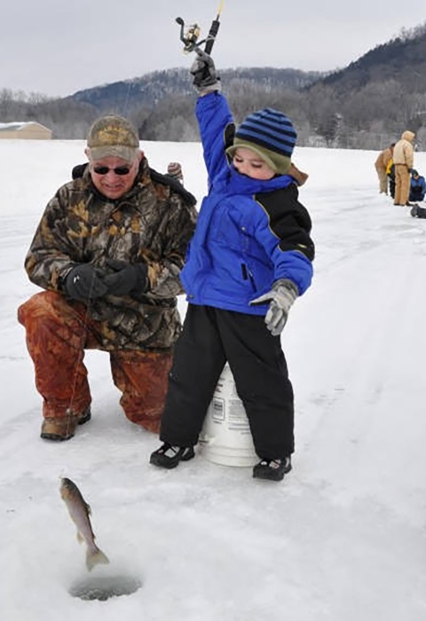 Young boy enjoying icing as he holds up his catch. 