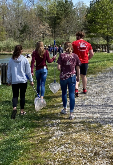 Students with nets walking by a creek 