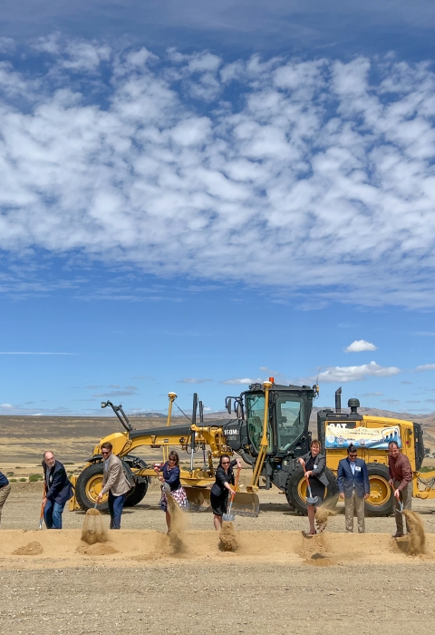 a group of people with shovels making a hold with a tractor behind them