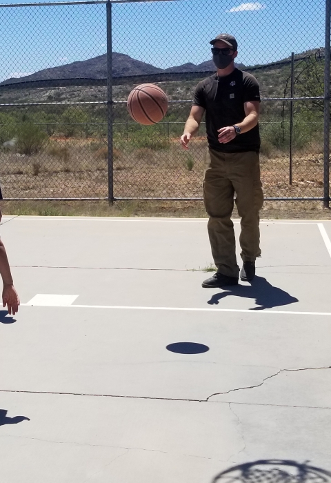 2 kids and adult play basketball on outside court