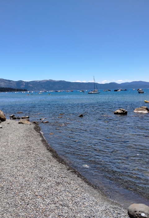 Shoreline of Lake Tahoe with boats in the distance.