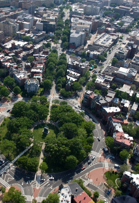 an aerial view of a city, with a circular layout in the middle. Trees engulf the circl