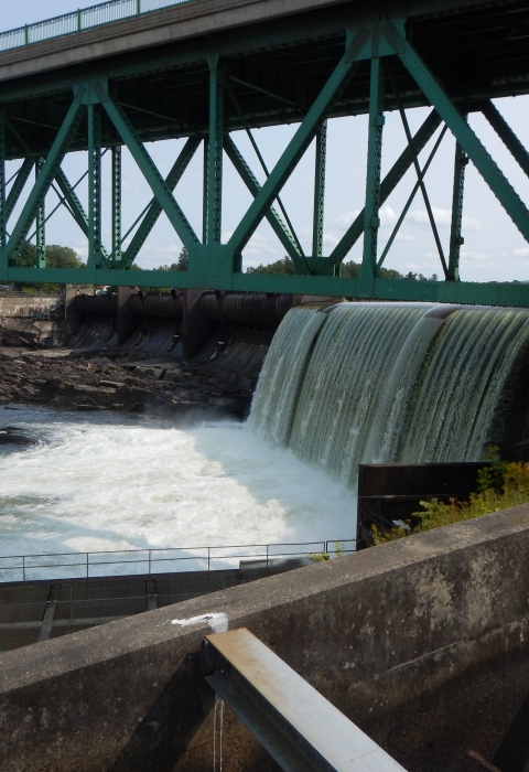 Dam with bridge overhead. Fish passage structures can be seen in the foreground