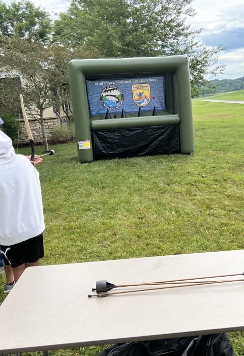 USFWS volunteers assisting kids with shooting archery at blow up targets